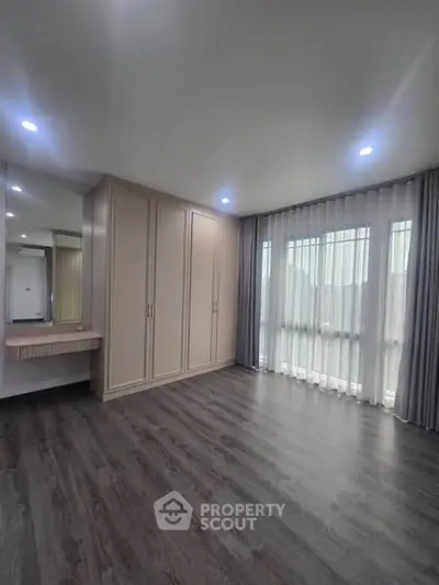 Spacious empty bedroom with large windows and elegant wooden flooring