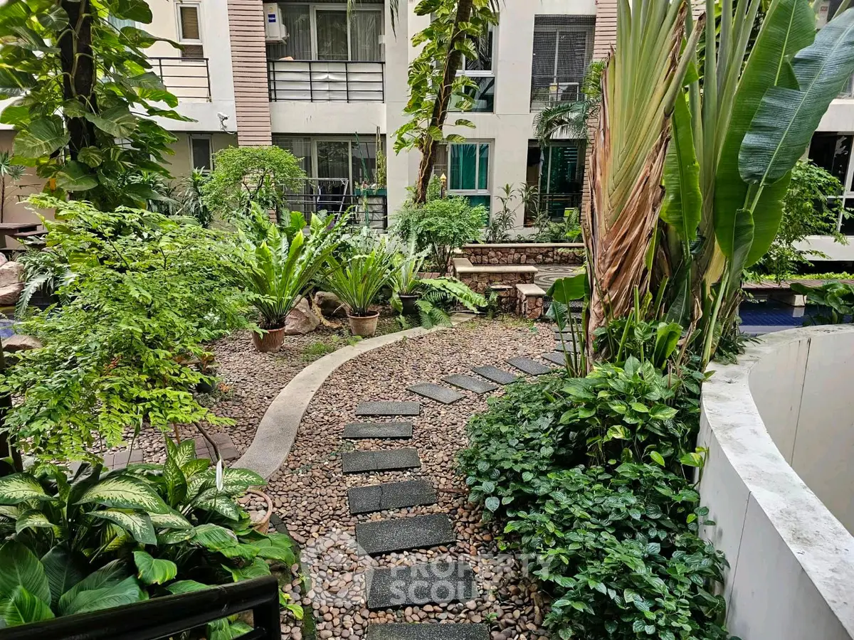 Lush garden pathway in modern residential complex with vibrant greenery and serene ambiance.