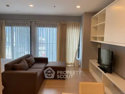Modern living room with large windows and stylish furniture in a high-rise apartment.