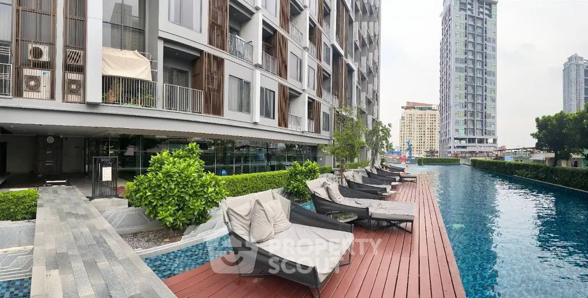 Luxurious apartment building with poolside lounge chairs and stunning city view.
