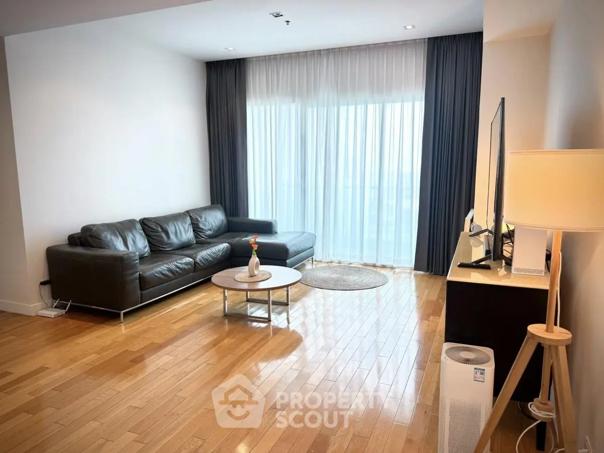 Spacious modern living room with sleek leather sofa and large window for natural light.