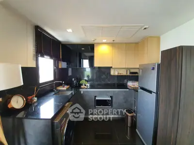 Modern kitchen with sleek black countertops, stainless steel appliances, and wooden cabinetry.