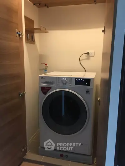Compact laundry space with modern LG washing machine in a cozy storage area.