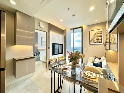 Modern open-plan living room with dining area and stylish decor, featuring a view of the bedroom and balcony.