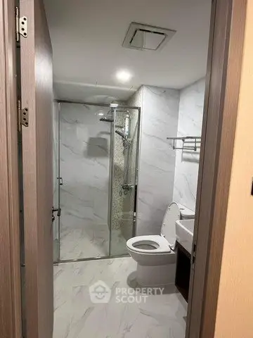 Modern bathroom with glass shower and marble tiles in a contemporary apartment.