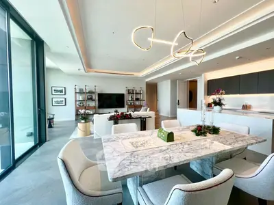 Luxurious open-plan living and dining area with modern lighting and elegant marble table.