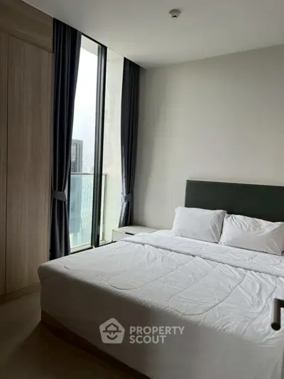 Modern bedroom with large window and elegant curtains in a high-rise apartment.