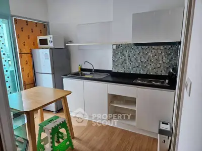 Modern kitchen with sleek cabinets and mosaic backsplash in a cozy apartment.