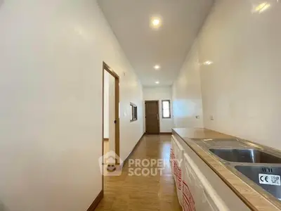 Spacious kitchen with wooden flooring and modern sink in a bright apartment.