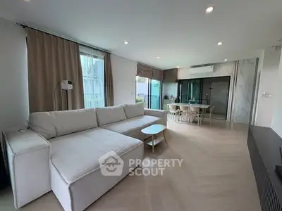 Spacious modern living room with large sofa and dining area, perfect for family gatherings.