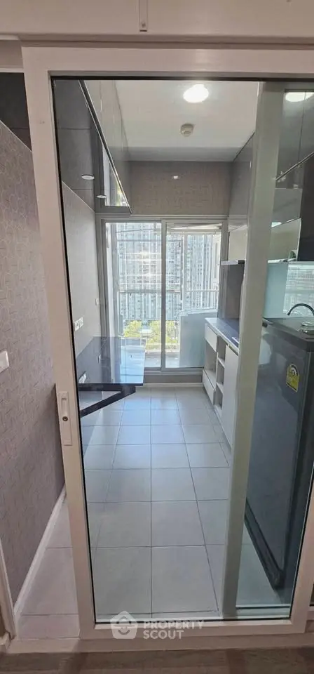 Modern kitchen with sleek design and city view, featuring a glass sliding door and contemporary appliances.
