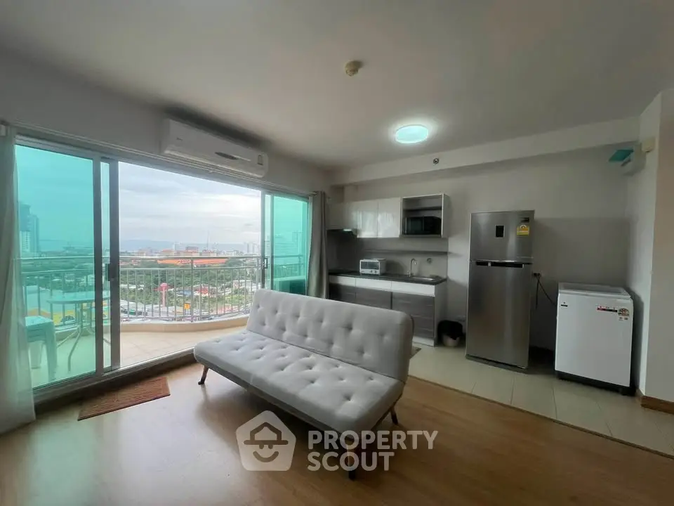 Modern living room with open kitchen and stunning city view from balcony.
