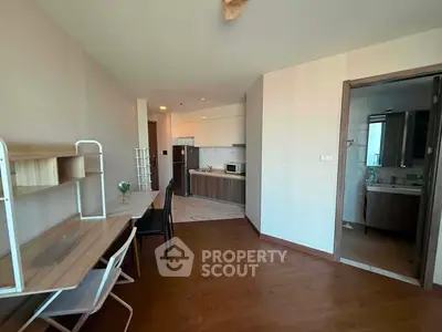 Modern apartment interior with open kitchen and study area, featuring wooden flooring and contemporary design.