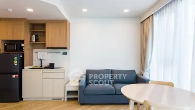 Modern living room with kitchenette, featuring sleek cabinetry and cozy seating area.