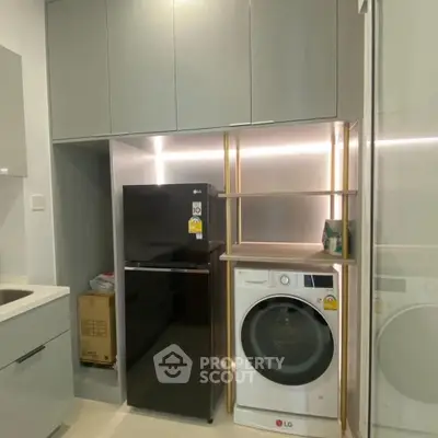 Modern kitchen with sleek cabinets, fridge, and washing machine in compact layout.