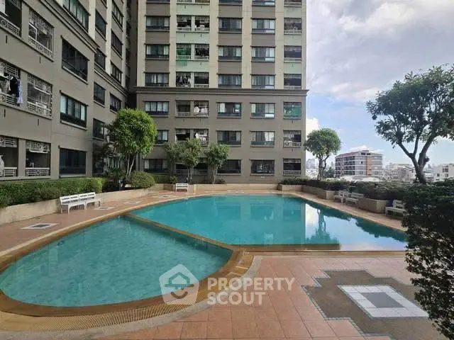 Modern apartment building with a spacious outdoor pool and lush greenery.