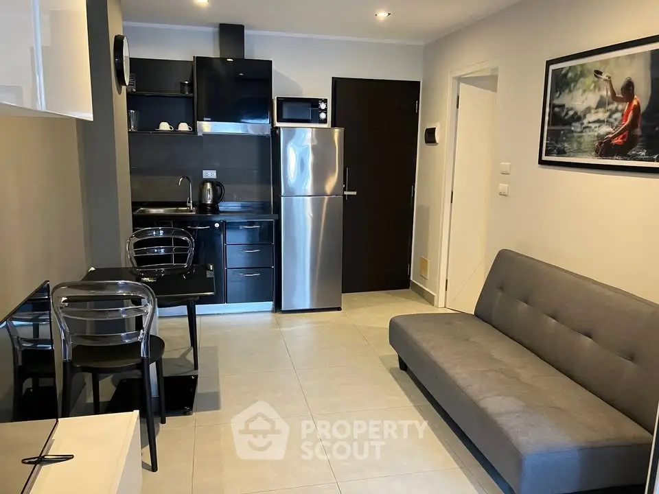 Modern studio apartment with sleek kitchen and cozy living area, featuring stainless steel appliances and stylish decor.