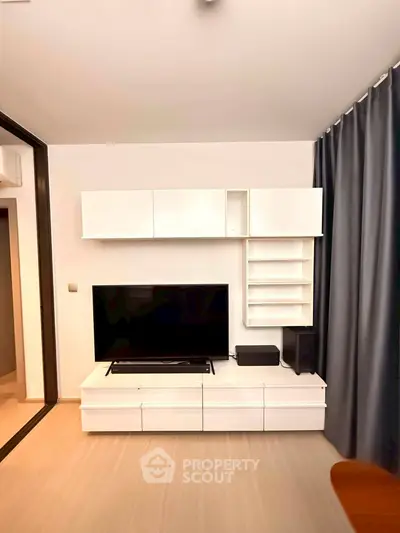 Modern living room with sleek white entertainment unit and large TV, perfect for stylish urban living.