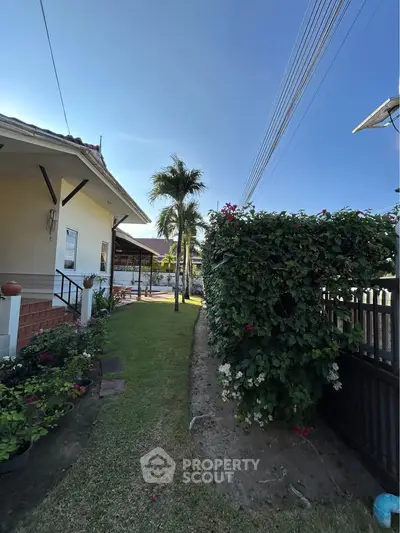 Charming suburban home with lush garden and palm tree, perfect for outdoor relaxation.