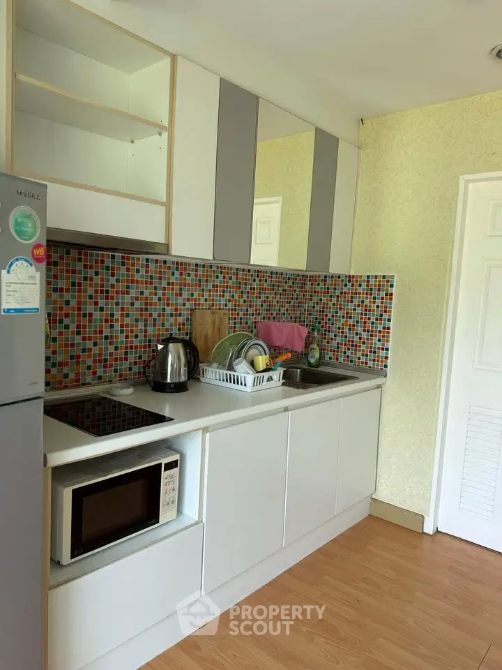 Modern kitchen with colorful backsplash and sleek appliances in a cozy apartment.