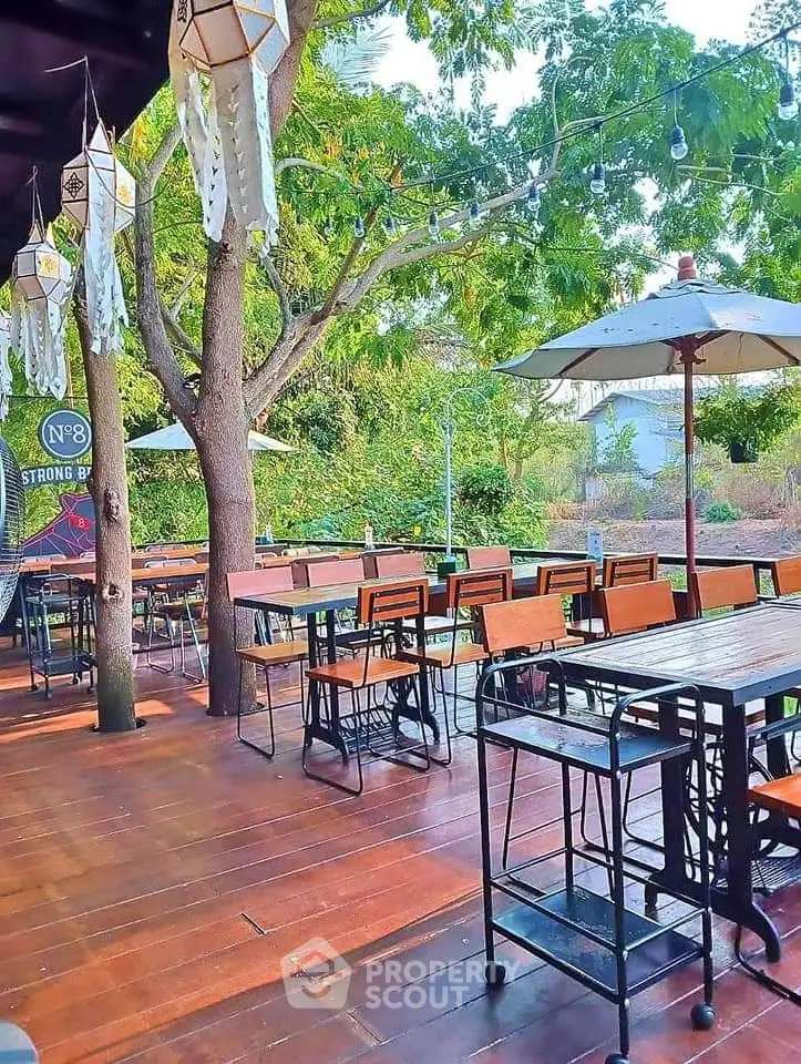 Charming outdoor patio with wooden deck and stylish seating under lush trees, perfect for relaxation.