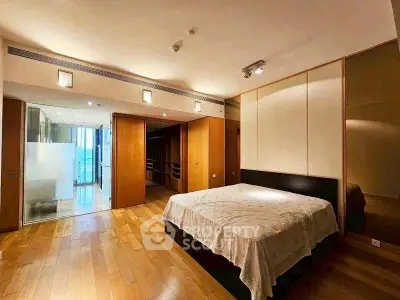 Spacious bedroom with wooden flooring and modern lighting in luxury apartment.