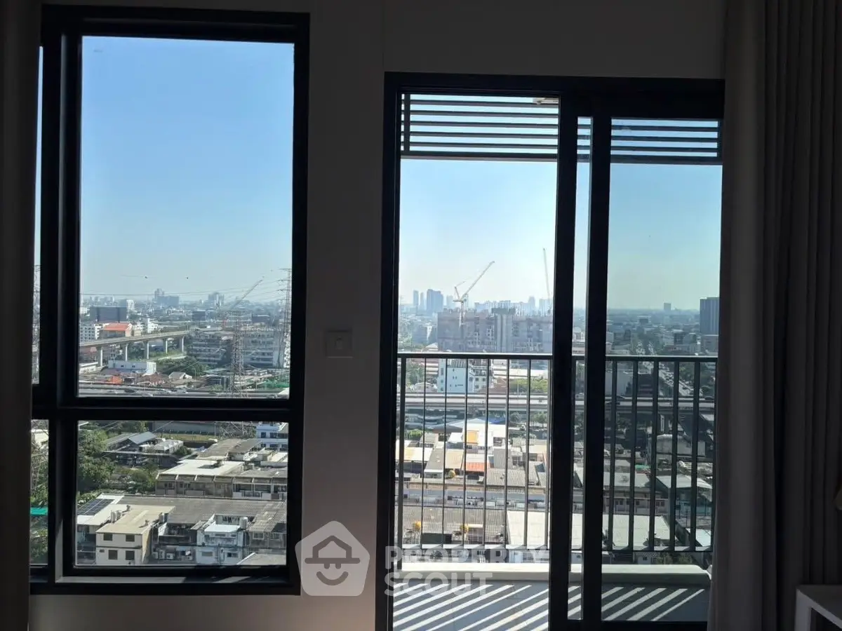 Stunning cityscape view from modern apartment balcony with large windows.