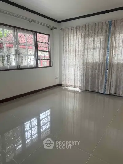 Spacious empty room with large windows and elegant curtains, perfect for customization.