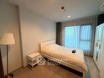Modern bedroom with cozy lighting and large window in a stylish apartment.