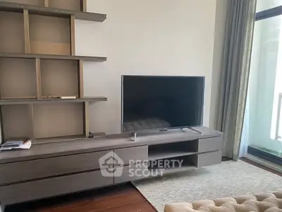 Modern living room with sleek TV stand and large flat-screen TV, featuring elegant shelving and natural light.
