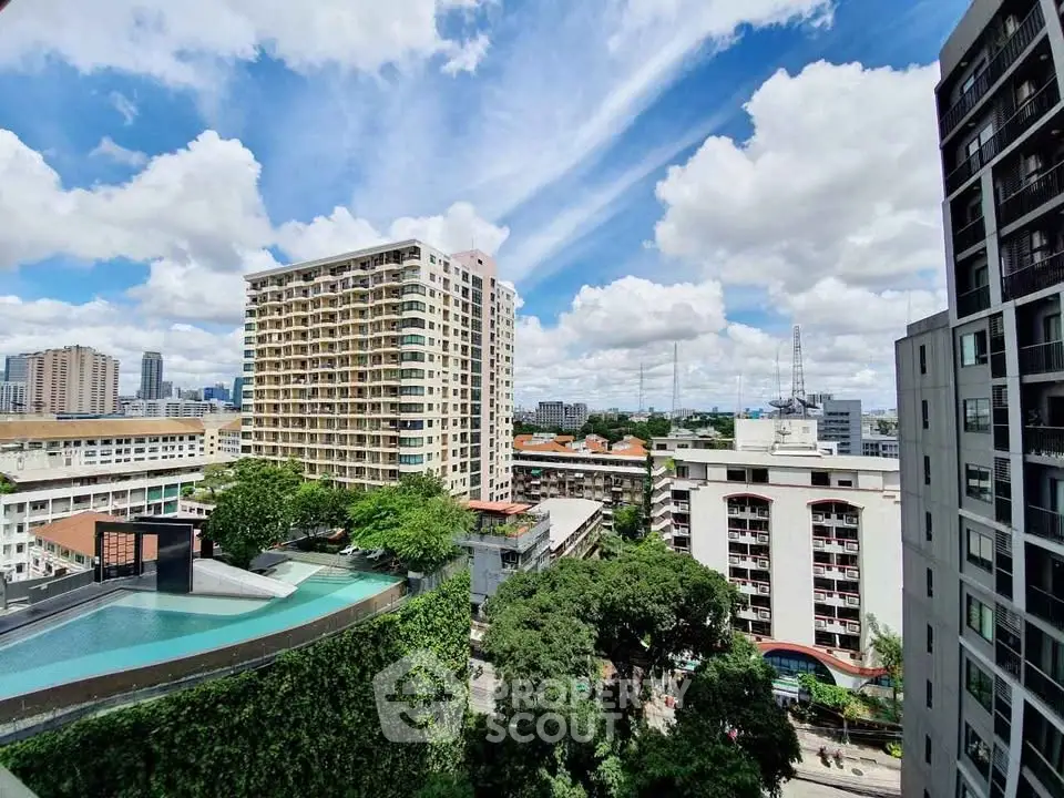 Stunning cityscape view from high-rise balcony with lush greenery and pool.