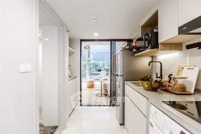 Modern kitchen with sleek appliances and open layout leading to a bright living area with balcony view.