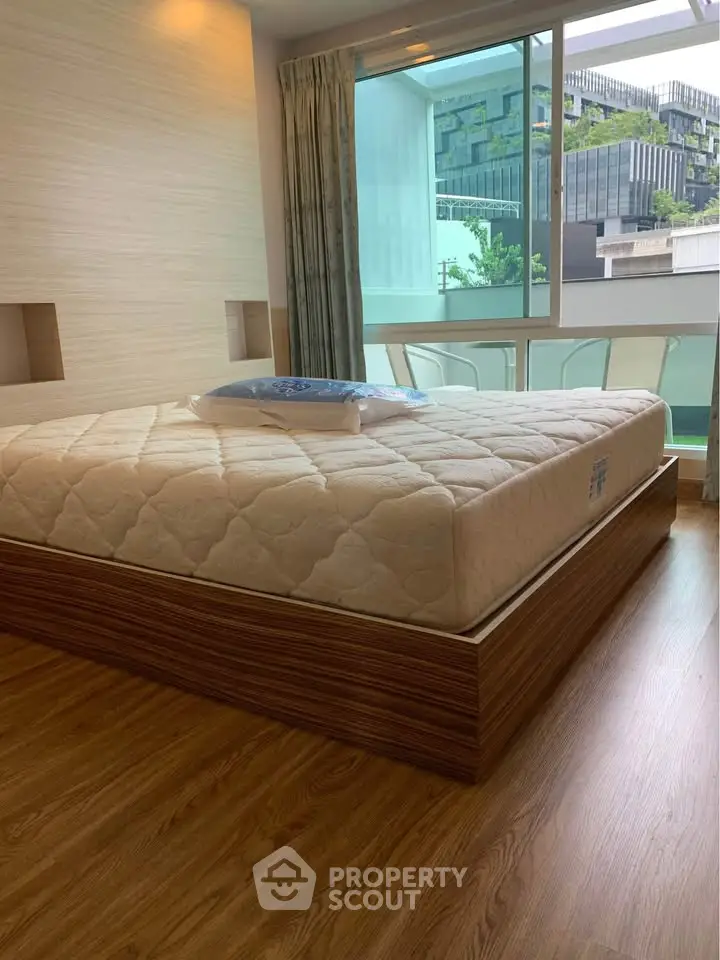 Modern bedroom with large window and stylish wooden flooring