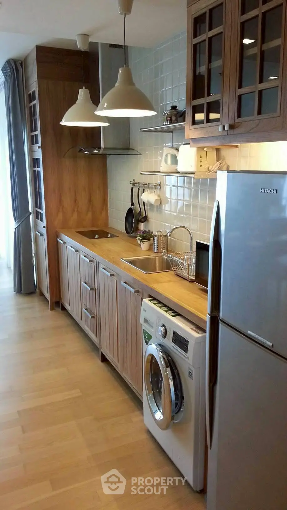 Modern kitchen with wooden cabinets, washing machine, and stainless steel fridge.
