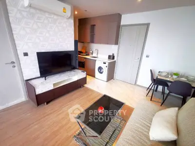 Modern living room with open kitchen, featuring a TV, washing machine, and dining area.