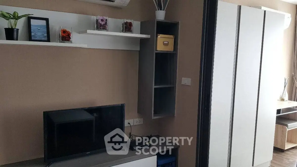 Modern living room with sleek furniture and wall-mounted TV in a cozy apartment.