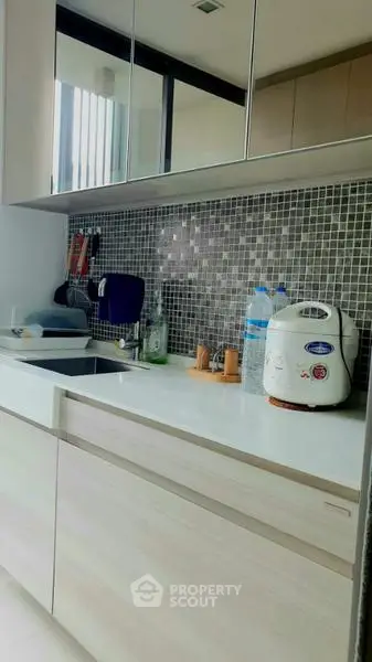 Modern kitchen with sleek cabinetry and mosaic backsplash, featuring essential appliances for a stylish culinary space.