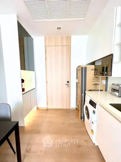 Modern kitchen with sleek appliances and wooden flooring in a stylish apartment.