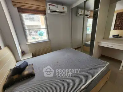 Cozy bedroom with large window, mirrored wardrobe, and air conditioning unit.