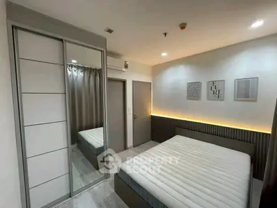 Modern bedroom with sleek design and ambient lighting, featuring a large mirrored wardrobe.