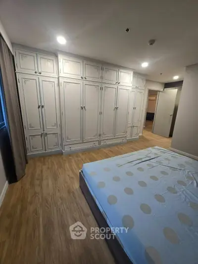 Spacious bedroom with elegant built-in wardrobes and cozy wooden flooring.