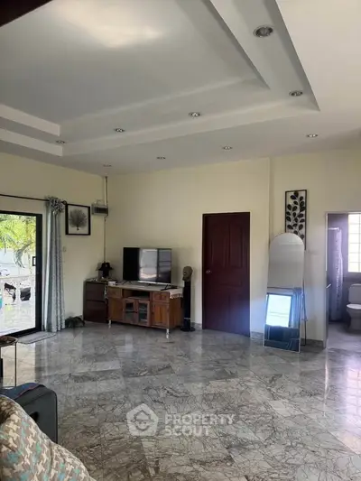 Spacious living room with marble flooring and modern decor, featuring a TV unit and large windows for natural light.