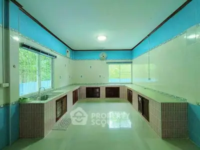 Spacious kitchen with closed layout and ample counter space, featuring vibrant blue and white tiles.