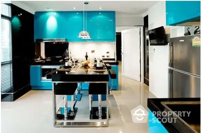 Sleek modern kitchen with vibrant blue cabinets, stainless steel appliances, and a stylish breakfast bar set in a luxurious home.