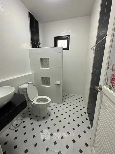 Modern bathroom with stylish black and white tile design and sleek fixtures.