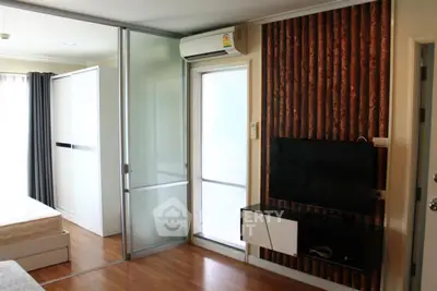 Modern bedroom with sliding glass doors and wall-mounted TV in stylish apartment.