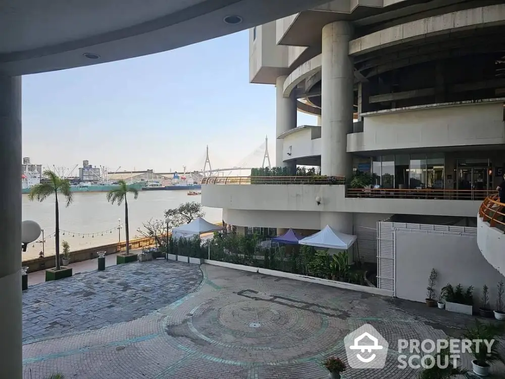 Stunning waterfront view from modern building with spacious terrace and lush greenery.