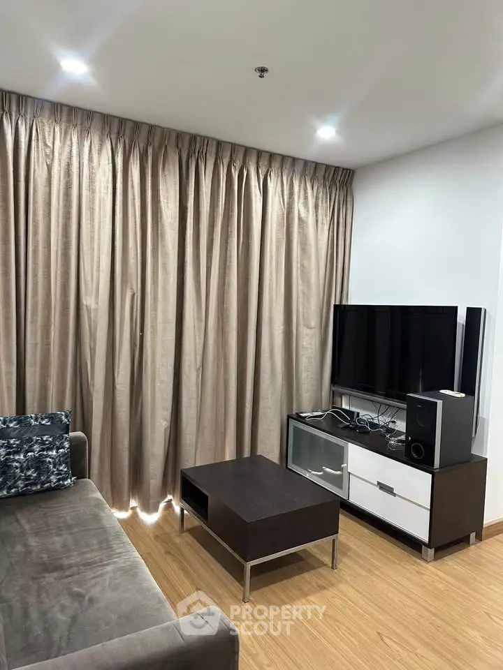 Modern living room with sleek furniture and entertainment setup, featuring elegant curtains and wooden flooring.