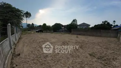 Spacious vacant land plot with potential for development, surrounded by lush greenery and residential homes.