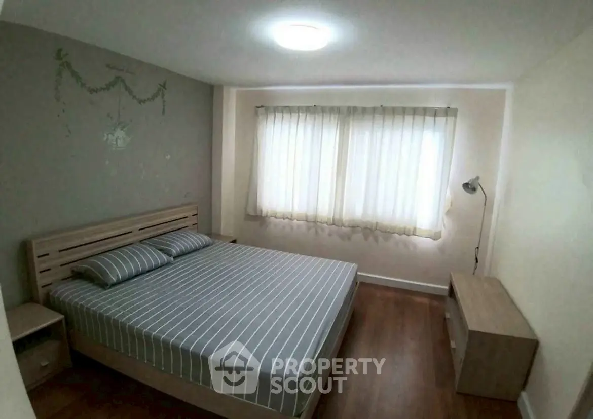 Cozy bedroom with striped bedding and natural light through curtains